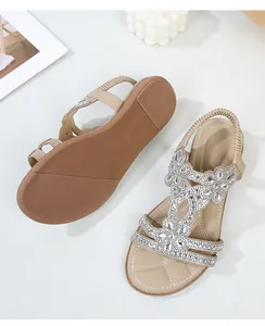 Dettaglio sandali piatti beige con motivi floreali di strass e cinturino elastico