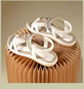Detail of white sandals with crossover straps, grey beads, and size 37 on the insole