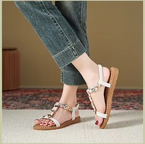 Details von flachen Boho-Sandalen mit bunten Webarbeitsriemen und Goldschieber am Fuß