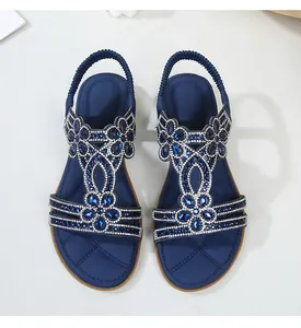 Dettaglio di sandali piatti boho blu con strass scintillanti e decorazioni floreali in gemma