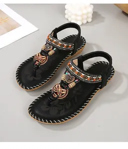 Detail van boheemse zwarte sandalen met oranje kralen en vlinder- en hartaccenten