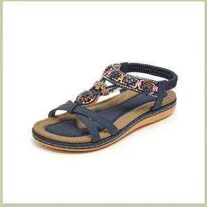 Detail der Boho-Flachsandalen mit metallischen Blumen und blauen Perlenriemen