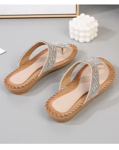 Detalle de sandalias planas bohemias de dedo con pedrería brillante y bordes cosidos