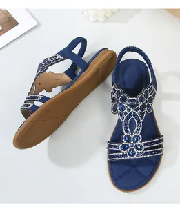 Dettaglio di sandali bassi blu navy con strass floreali e cinturino elastico al tallone
