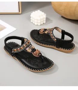 Detail van boho platte sandalen met oranje kralen en metalen vlinderversiering