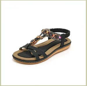 Detail von Boho-Flachsandalen mit bunten Perlen und metallischen Blumen-Verzierungen