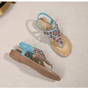 Close-up of blue bohemian flat sandals with sparkling rhinestones and floral beadwork