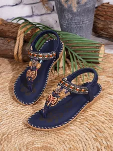Detail van blauwe bohemien platte sandalen met kralen en hartjes op een geweven mat