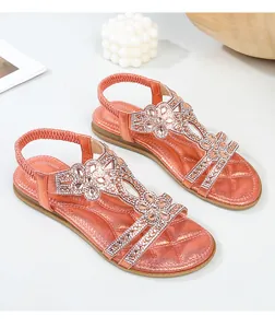 Dettaglio di sandali corallo con fiori di strass, suola trapuntata e cinturino elastico