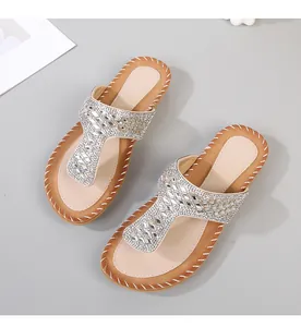 Detalle de sandalias planas bohemias con diseño de tira en T decorada con pedrería