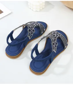 Dettaglio dei sandali blu scuro con strass a fiori e cinturino elastico sulla caviglia
