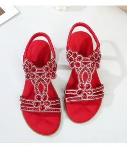 Dettaglio di sandali bohémien rossi con strass scintillanti e motivo floreale chic