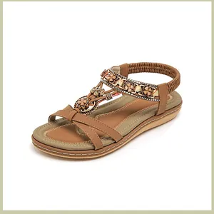 Detailansicht der braunen flachen Sandalen mit Metallblumen und Glitzer-Strasssteinen
