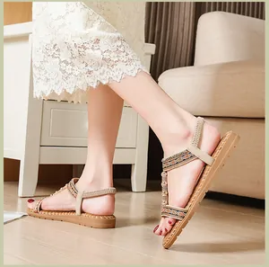 Detalle de sandalias planas bohemias con tiras tejidas y cuentas en una modelo