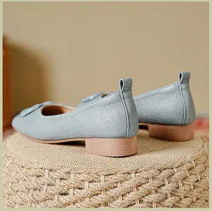 Detailweergave van lichtblauwe leren loafers met getextureerd bovenwerk en platte houten hak