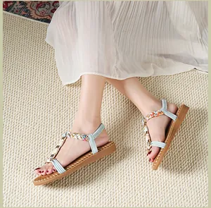 Detail von hellblauen Riemchen-Sandalen mit buntem Webmuster und weißen Perlen
