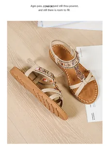 Detail of beige flat sandals with colorful beads, metallic butterflies and cross straps