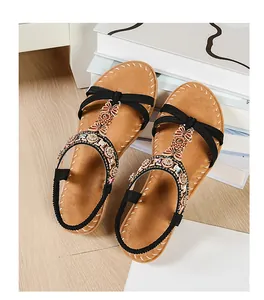 Detailed close-up of Bohemian flat sandals with sparkling rhinestones and floral metal charms