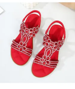 Dettaglio dei sandali bassi rossi con strass bohémien e cinturino elastico sul tallone