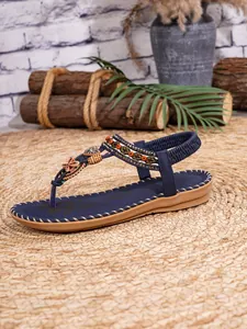 Detail van bohemian platte sandalen met gekleurde kralen, hartjes en bloemenaccenten