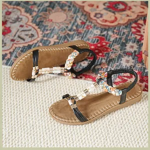 Details von flachen Sandalen mit Strassakzenten und ethnisch geflochtenem Fersenriemen