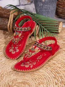 Detailweergave van rode boho-sandalen met kleurrijke kralen en vlinderversiering