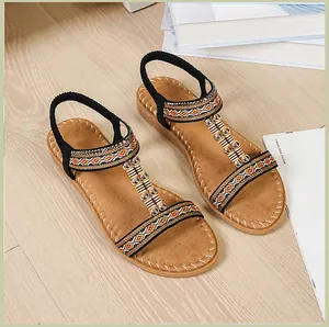 Detalle de sandalias planas bohemias con correas trenzadas étnicas y cuentas doradas