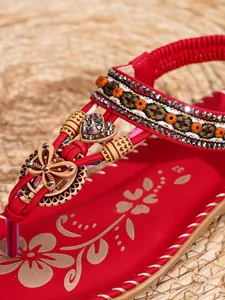 Detail van rode Boheemse platte sandalen met houten vlinders en glanzende strassteentjes