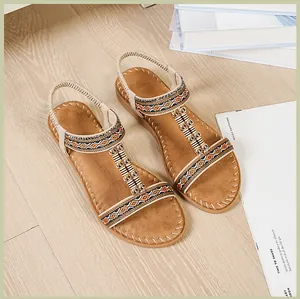Detalle de sandalias planas bohemias con tejidos étnicos y lentejuelas sobre madera