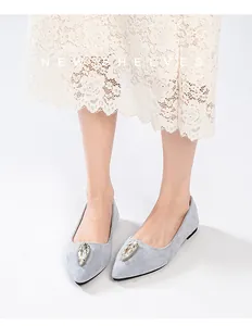 Gros plan sur une chaussure plate pointue en daim avec boucle en cristal étincelant