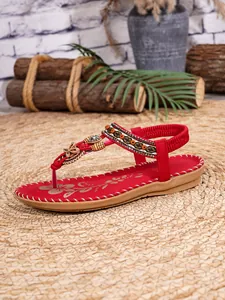 Detail van rode Bohemian sandalen met fijn kralenwerk en houten vlinderaccenten