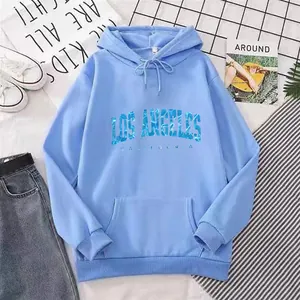 Detail of light blue hoodie with Los Angeles lettering, styled with denim and sneakers