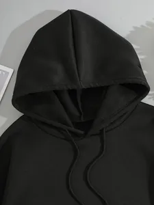 Détail du sweat à capuche noir avec cordon de serrage et coutures d'épaules tombantes