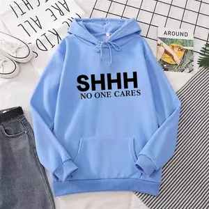 Flat lay of light blue hoodie with SHHH NO ONE CARES print and lifestyle props