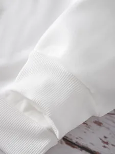 Détail du poignet en coton côtelé blanc montrant la texture fine du tricotage serré