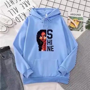 Détail d'un sweat à capuche bleu clair avec texte Shine et illustration de portrait