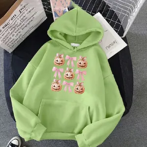 Macro detail of green hoodie featuring cute pumpkin prints and a large kangaroo pocket