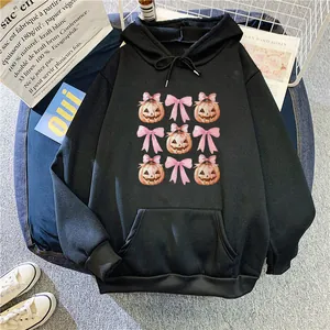 Detail of black hoodie featuring pumpkin and bow prints with a kangaroo pocket and drawstrings