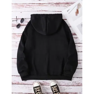 Flat lay of a black oversized zip-up hoodie with ribbed cuffs on a wooden background