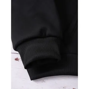Close-up of ribbed cuffs and hem on a black oversized zip-up hoodie with clean stitching