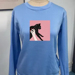 Detail shot of light blue crewneck sweatshirt featuring a cute cat graphic print