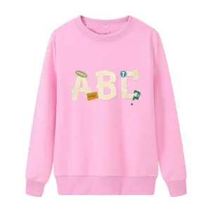 Détail d'un sweat rose avec broderie appliquée ABC et encolure ronde à bords-côtes