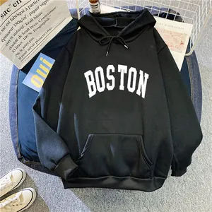Close-up of black oversized hoodie featuring white BOSTON lettering and kangaroo pocket