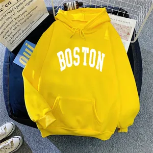 Flat lay of yellow hooded sweatshirt with white Boston lettering and lifestyle props
