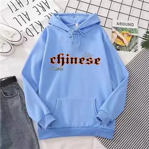 Détail du sweat à capuche bleu clair oversize avec texte gothique noir et orange