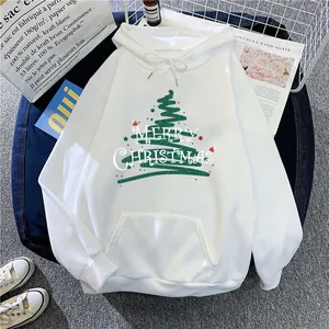Flat lay of white Christmas hoodie with green tree print and festive decor props