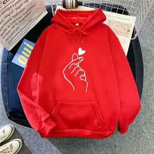 Detail of red oversized hoodie featuring heart gesture print and soft cotton fabric texture