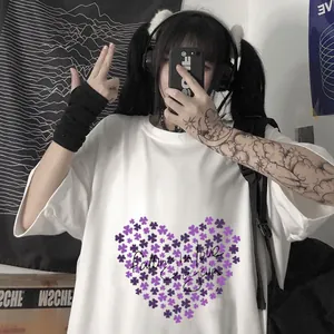 Détail d'un t-shirt blanc oversize avec imprimé trèfle en cœur violet et lettrage noir