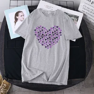 Détail d'un t-shirt gris clair avec imprimé cœur violet et slogan sur un support grillagé