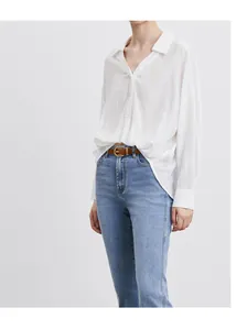 Detail eines braunen Ledergürtels mit goldener Hufeisenschnalle an hellblauer Jeans
